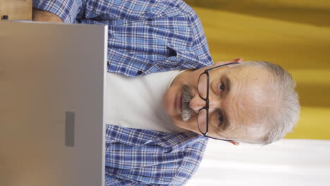 Vertical-video-of-Old-man-looking-at-laptop-in-amazement.